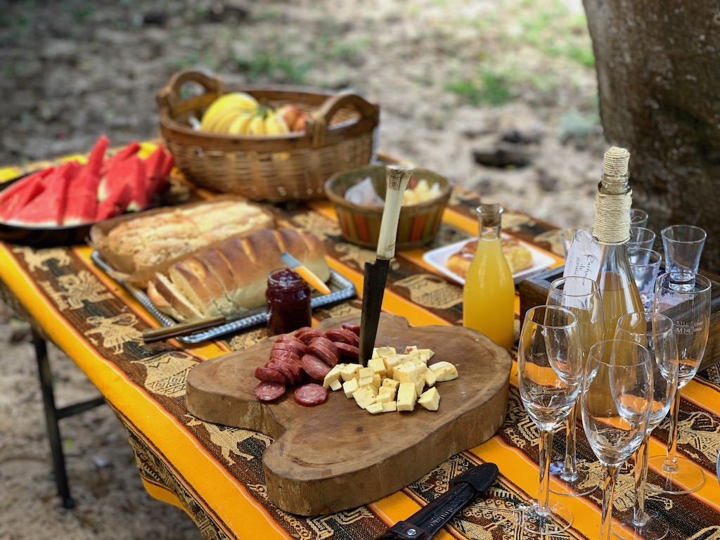 mesa de piquenique com frios, pães, frutas e bebidas