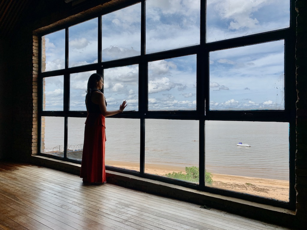 mulher parada em frente a janela com vista para rio