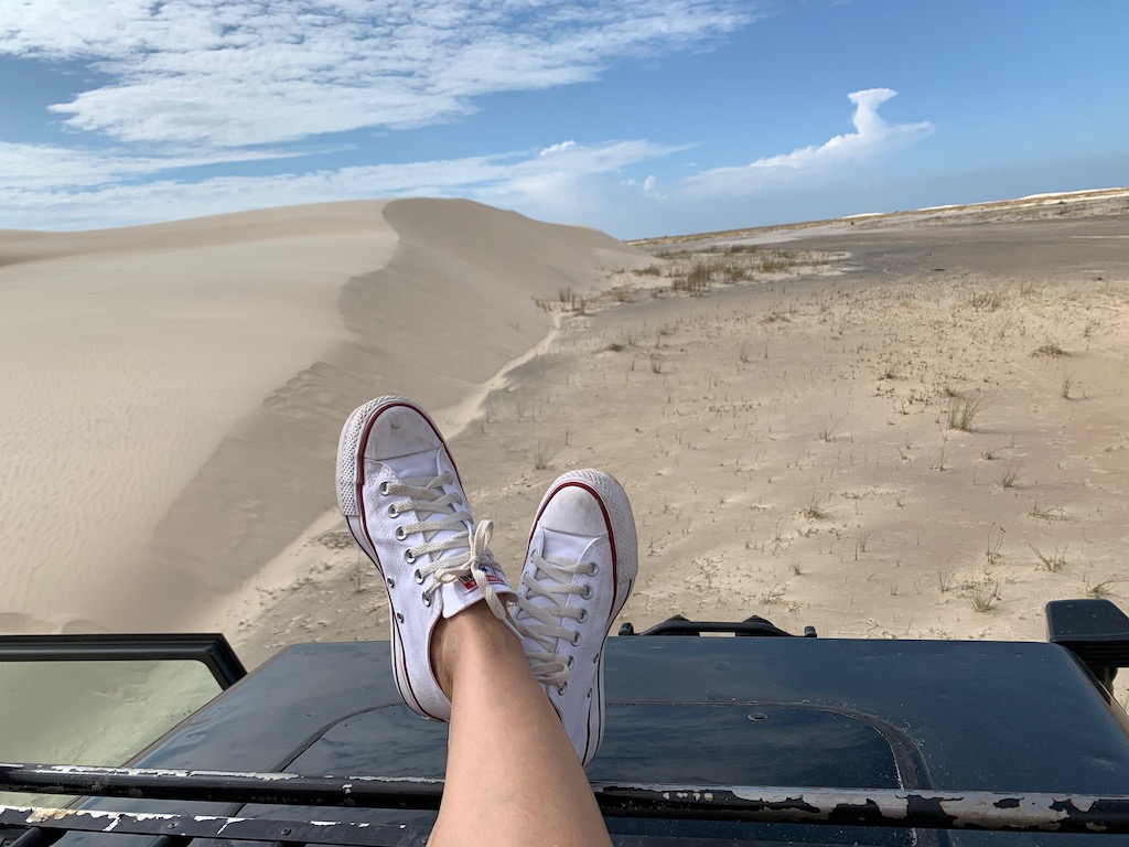 pés cruzados em cima de 4x4 com vista para a areia