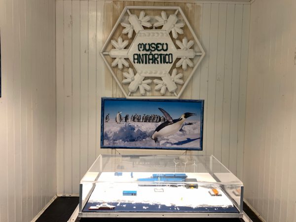 maquete de estação de trabalho na antártica e quadro de pinguins ao fundo