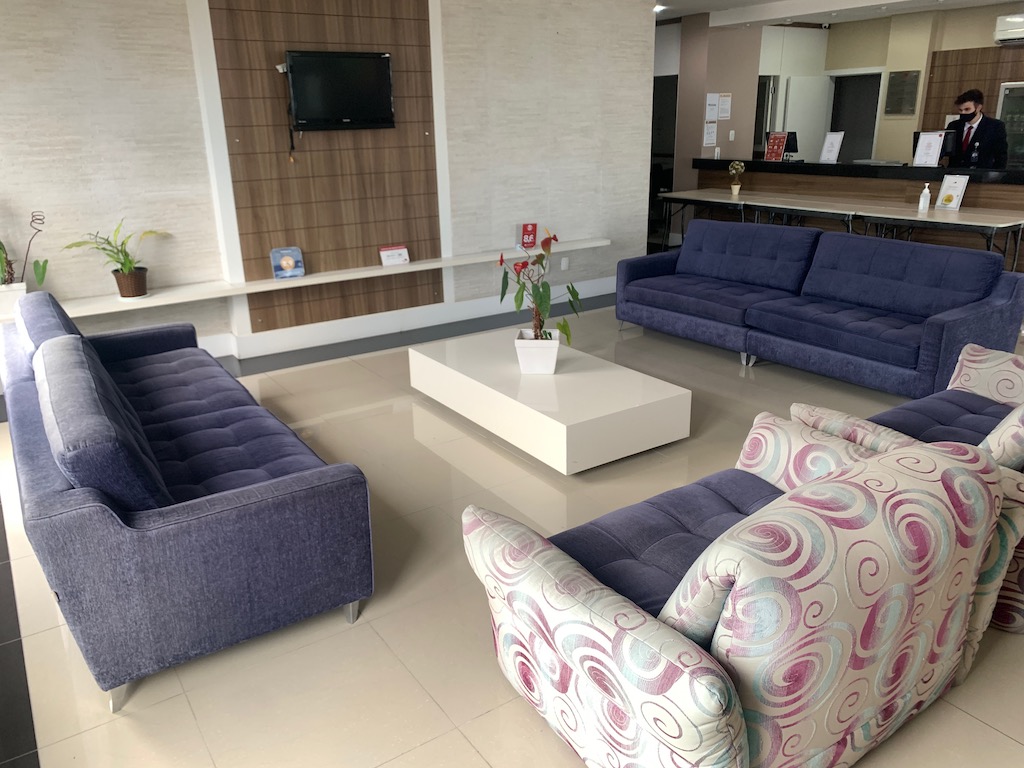 lobby de hotel com sofás, mesa, TV e recepção