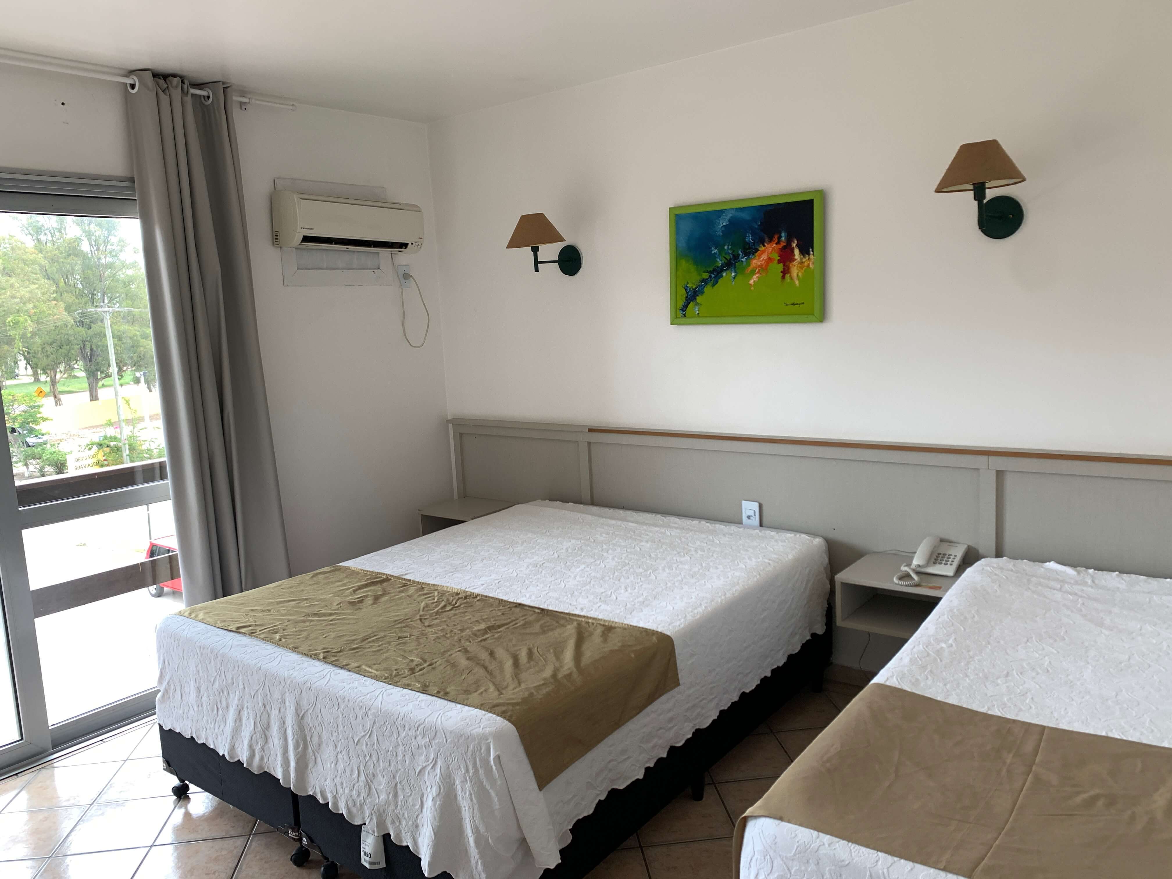 Quarto do hotel Bertelli, com duas camas, quadro, luminária e ar condicionado