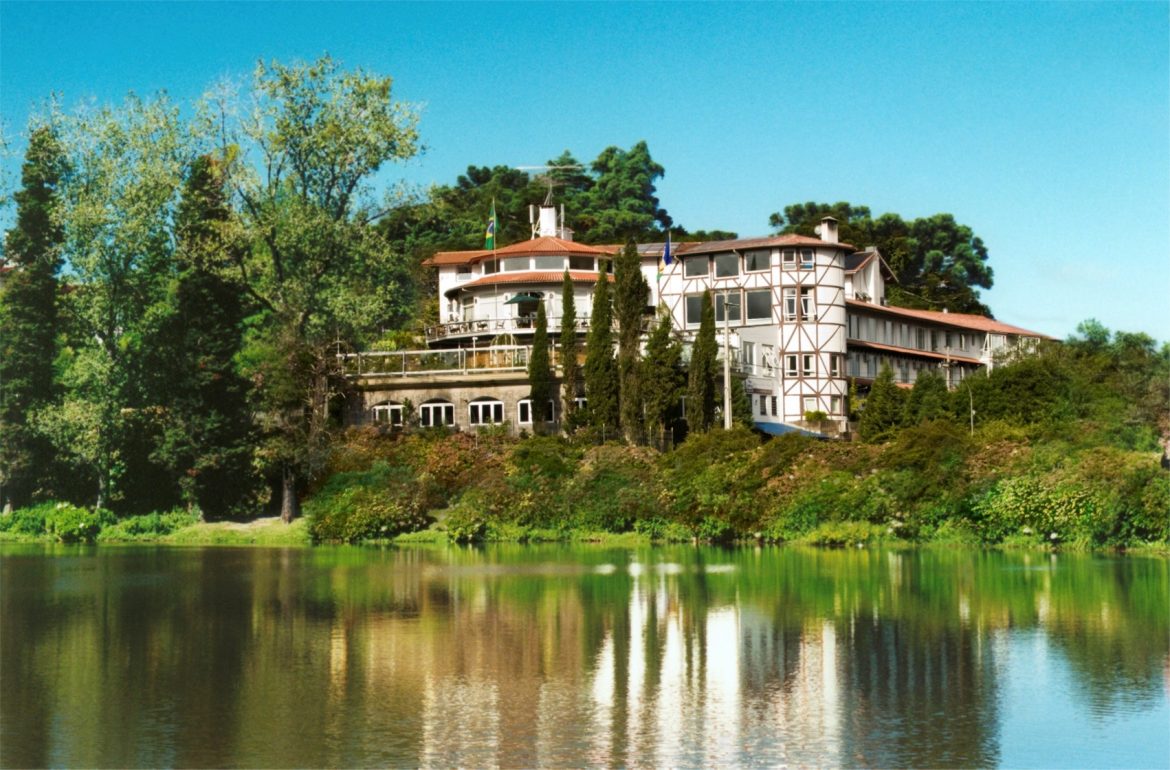 hotel localizado em frente a um lago, com árvores e céu azul