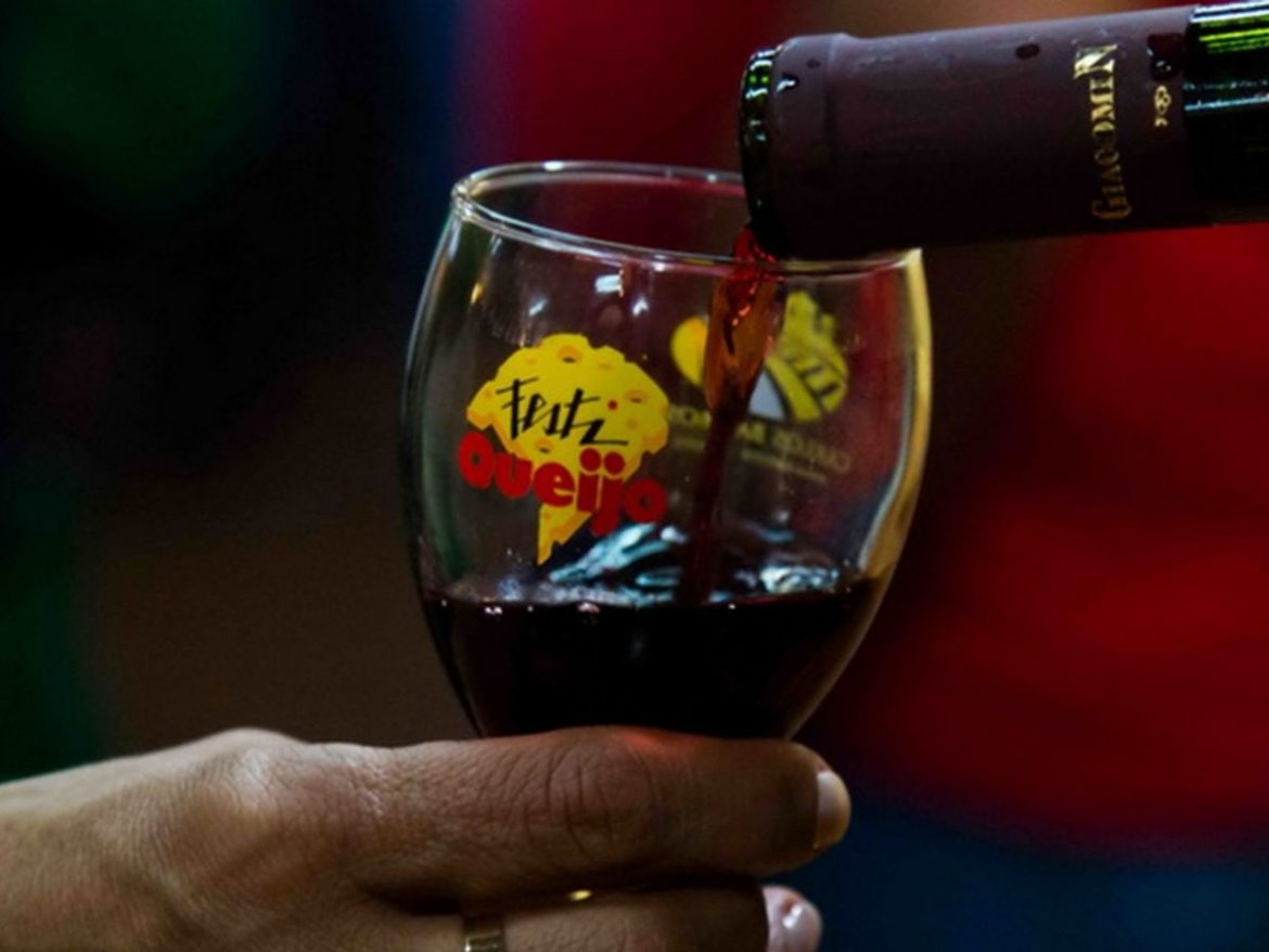 Festiqueijo 2022: na foto há uma taça com o nome do festiqueijo estampado e alguém servindo vinho