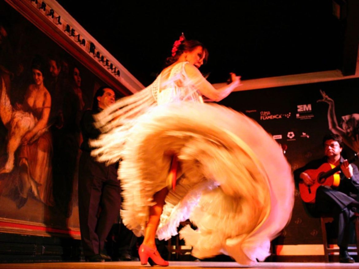Na foto uma mulher dança balançando o seu vestido que possui uma saia com diversas camadas